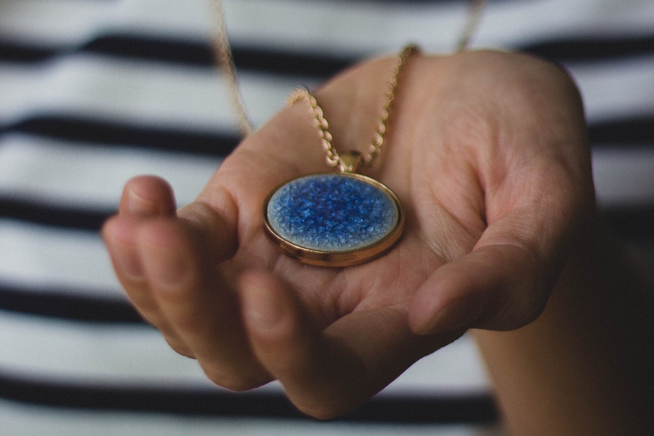 Someone holding up a blue gemstone necklace